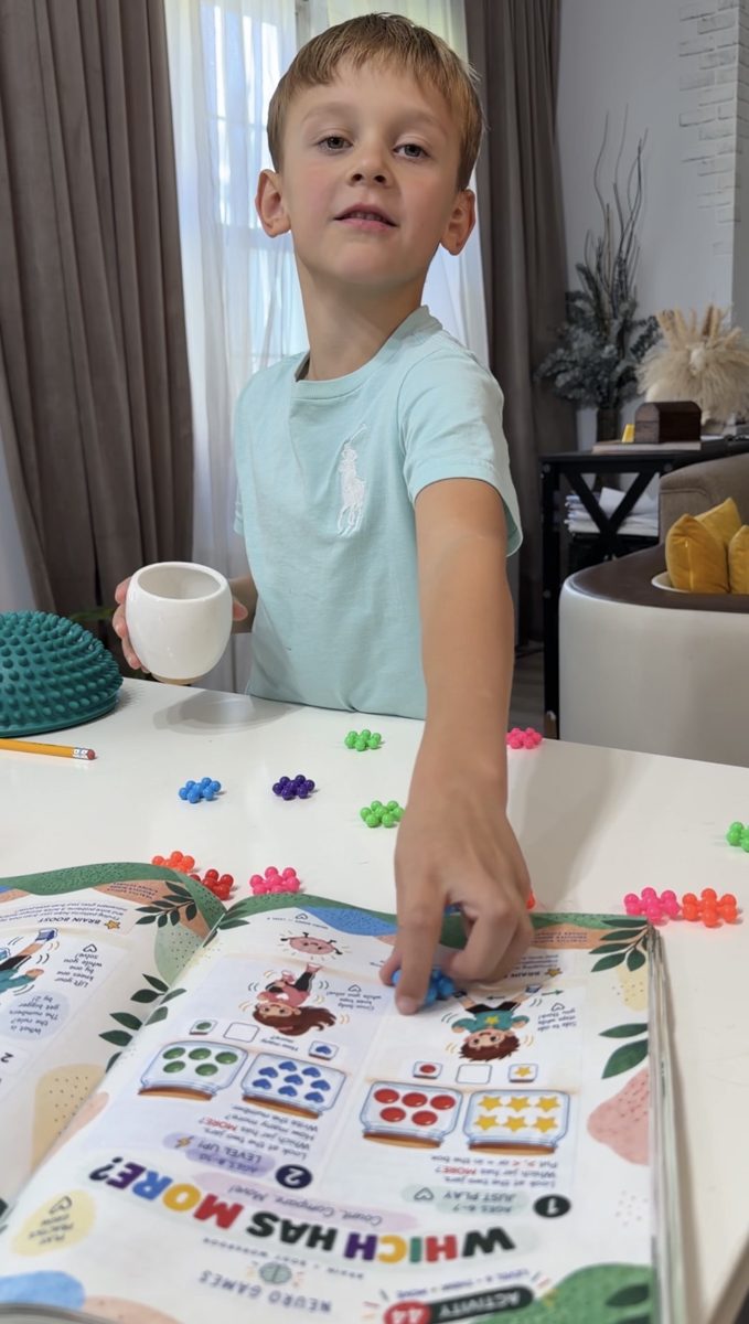 A boy places beads on a Which Has More? page