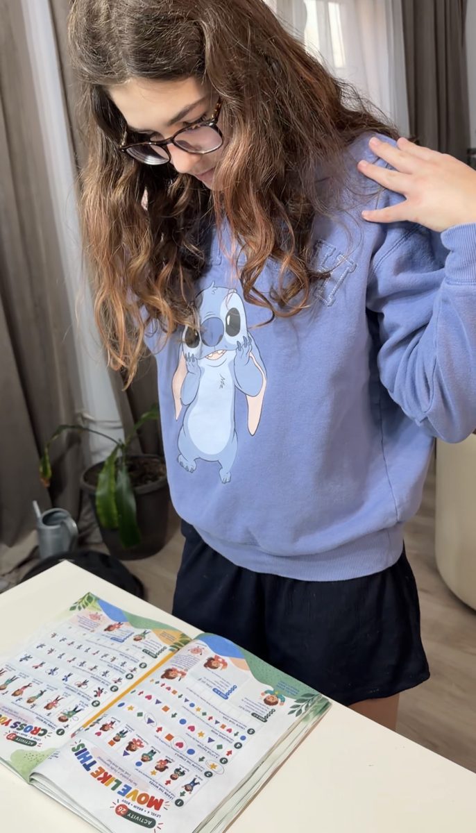 A girl does a movement from the book, hand on her shoulder