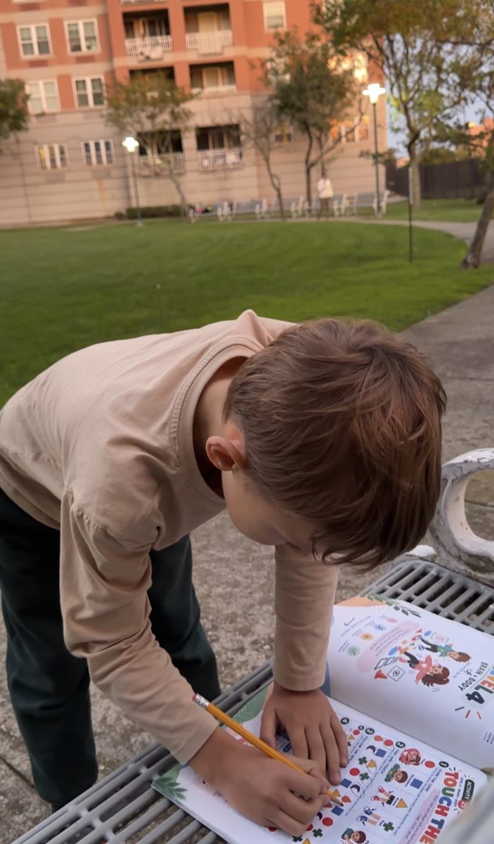 A boy works on a Neuro Games page outdoors on a bench