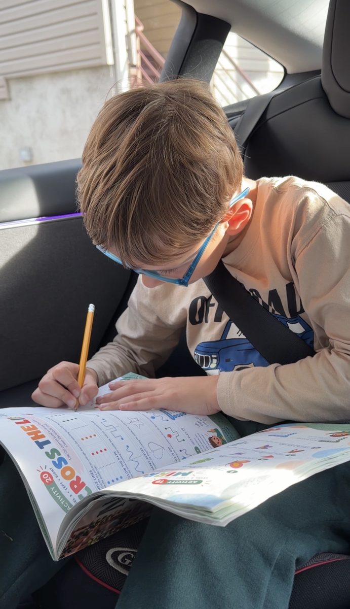 A boy solves a Neuro Games page with a pencil in the car
